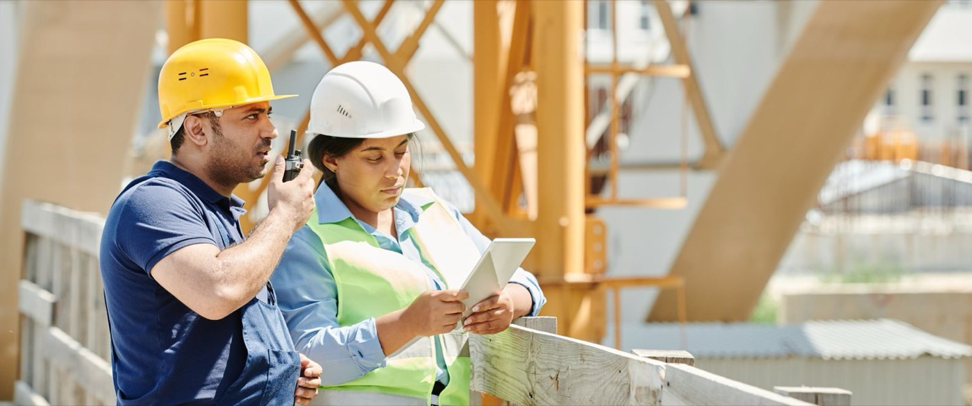 Zwei Fachkräfte stimmen sich auf der Baustelle mit einem Tablet ab