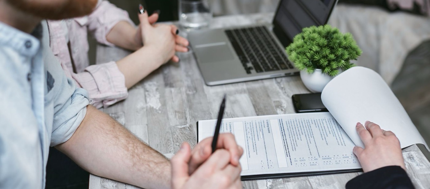 Beratungsgespräch am Tisch mit Unterlagen und Laptop